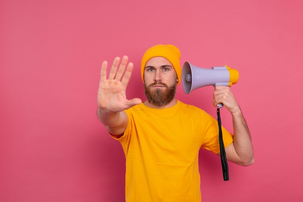 Free Photo european man hold megaphone show stop sign on pink background