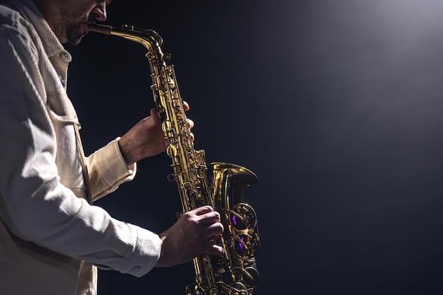 A European man plays the saxophone in the dark