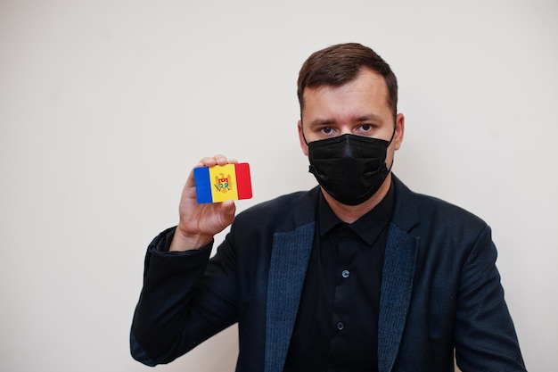 European man wear black formal and protect face mask hold Moldova flag card isolated on white background Europe coronavirus Covid country concept