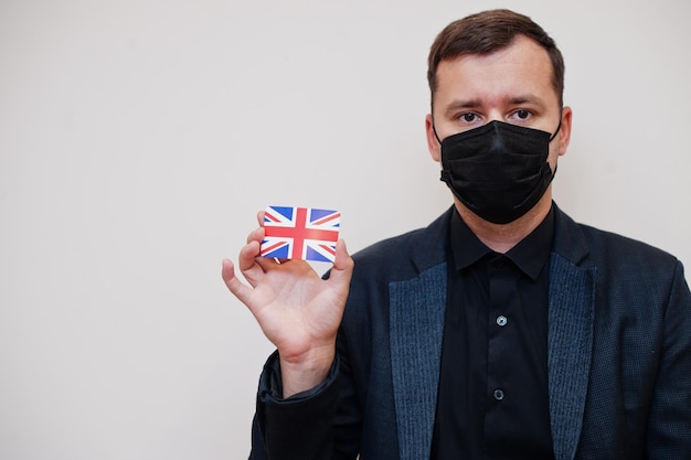 Free photo european man wear black formal and protect face mask hold united kingdom flag card isolated on white background europe coronavirus covid country concept