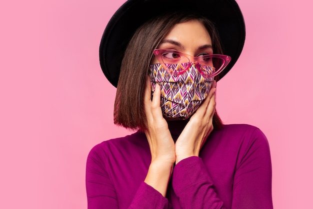 European model dressed protective stylish face mask. Wearing black hat and sunglasses.