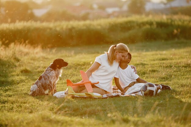 European mother and african son. Family in a summer park. People sitting on the blanket.