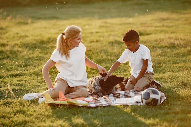 European mother and african son. Family in a summer park. People sitting on the blanket.