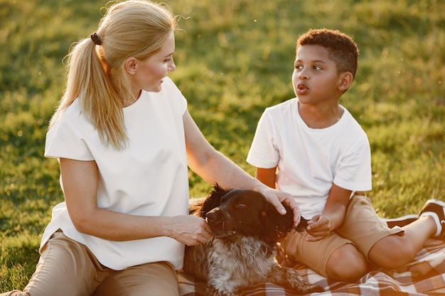 Free Photo european mother and african son. family in a summer park. people sitting on the blanket.