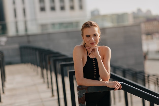 european woman posing at camera with smile while training outside in sunny day