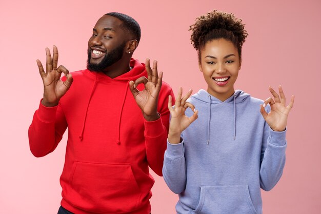 Everything perfect. Charming loving two couple relationship african american girlfriend boyfriend showing okay ok excellent gesture smiling approval assure parents they fine, pink background