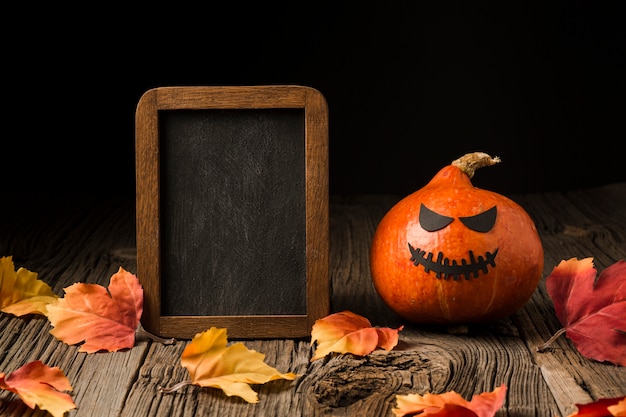 Free photo evil halloween pumpkin surrounded by leaves