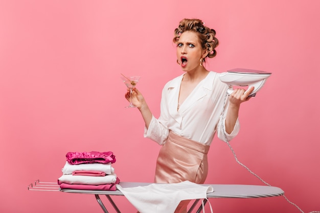 Evil housewife in business outfit holding iron and martini glass