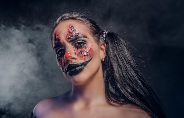 Evil psycho clown makeup looks especially creepy in a smoke over dark background.