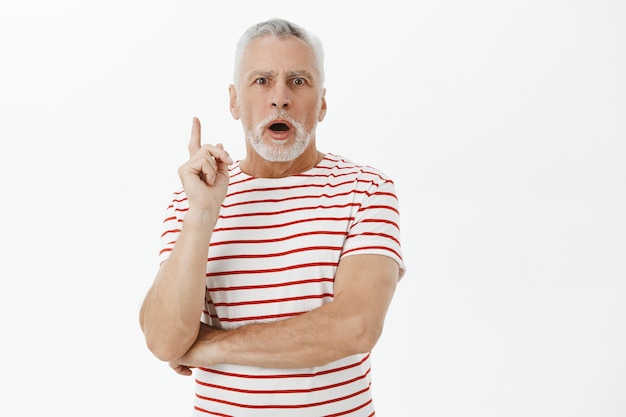 Excited bearded grandfather raising index finger, have idea, suggestion