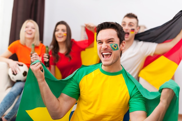 Free photo excited brazilian man with her friends cheering football match