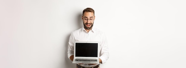 Excited businessman showing something on laptop screen standing happy over white background