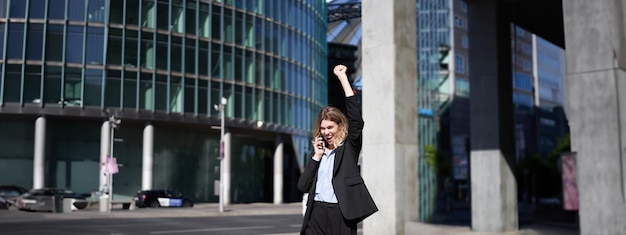 Free photo excited businesswoman receives great news celebrating while talking on mobile phone corporate woman