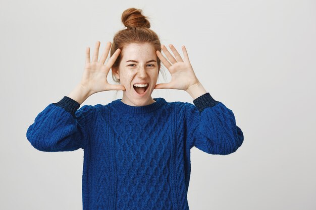 Excited charismatic redhead woman smiling and showing hands near face