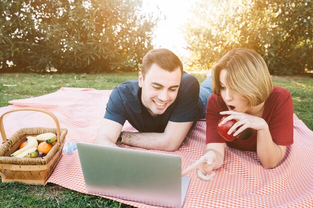 Excited couple browsing laptop on picnic