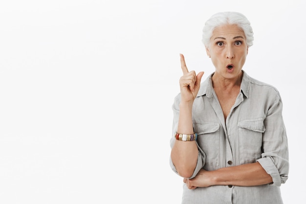 Excited elder mother raising finger eureka gesture, have idea, think-up plan