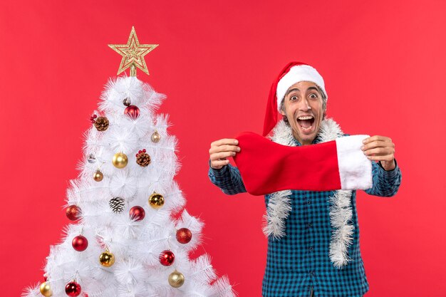 Excited extremely emotional young man with santa claus hat in a blue stripped shirt and holding christmas sock