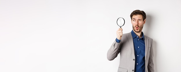 Excited funny guy in suit look through magnifying glass aside checking out awesome thing found somet