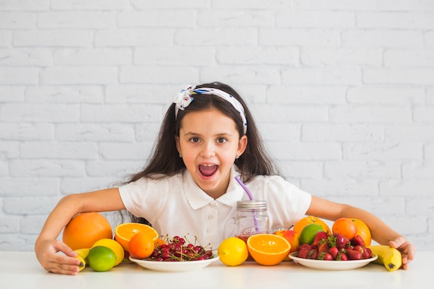 Free photo excited girl covering the colorful fresh organic fruits