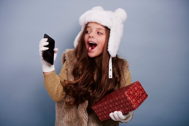 Excited girl with mobile phone and gift box