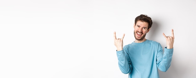 Free photo excited handsome man celebrating having fun and showing rock on horns gesture enjoing party smiling