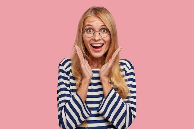 Free photo excited happy blonde woman posing against the pink wall