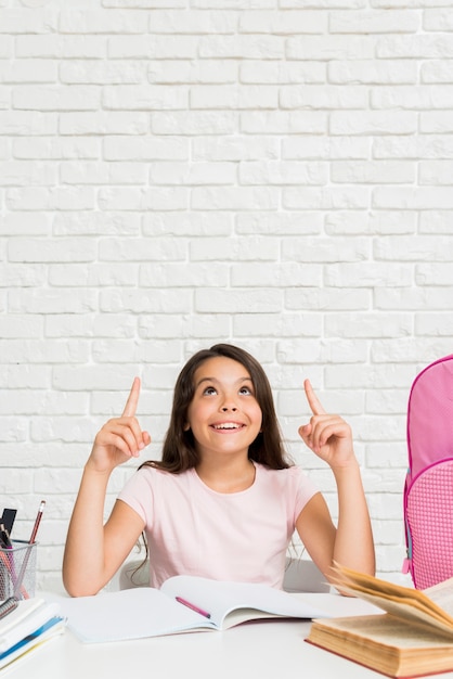 Excited Hispanic schoolgirl thinking at homework