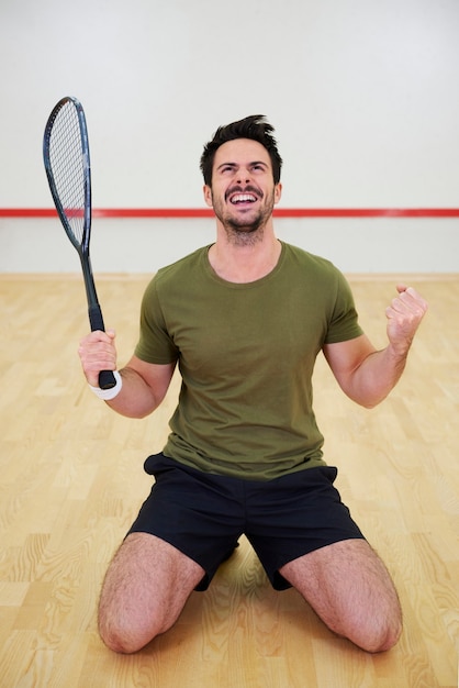 Excited male squash player celebrating on court