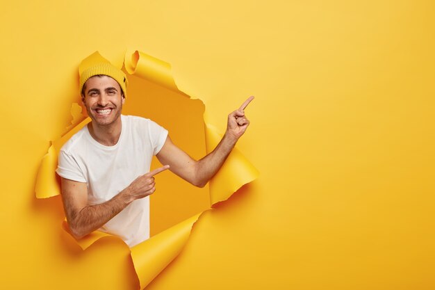 Excited pleased young man in casual outfit, shows something great on blank space