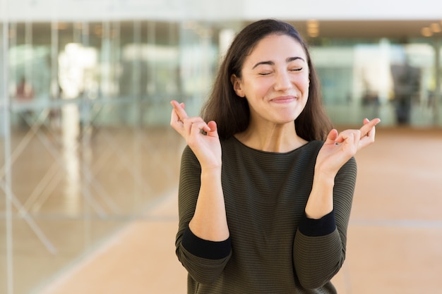 Free photo excited positive beautiful woman keeping fingers crossed