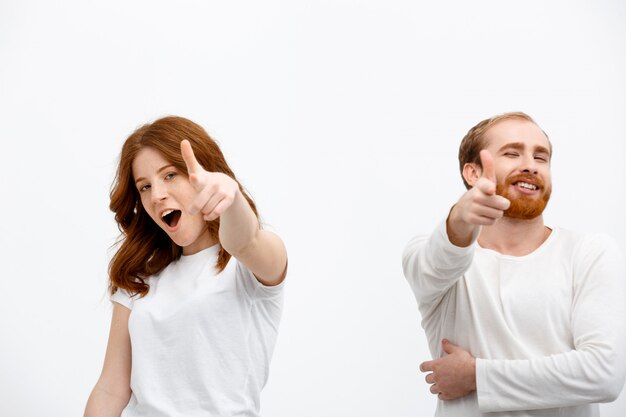 Excited redhead man and woman pointing at front