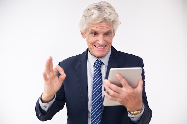 Free photo excited senior businessman looking at touchpad