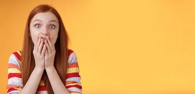 Free photo excited shocked redhead speechless girl like gossiping standing emotional astonished hear amusing story gasping full disbelief cover mouth palm amazed posing orange background impressed