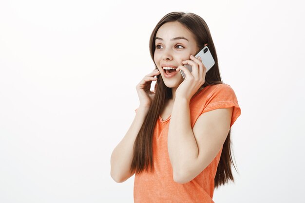 Excited smiling attractive girl talking on mobile phone and looking amused