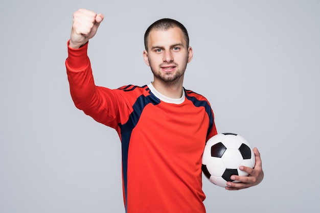 Excited soccer player in red t-shirt holding a football victory concept isolated on white