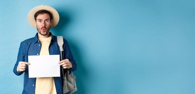 Free photo excited tourist in straw hat holding empty piece of paper and looking amused going on summer travel