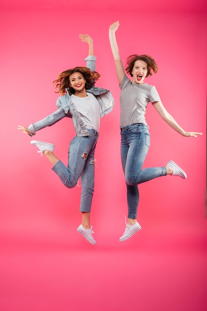 Excited two ladies friends jumping isolated