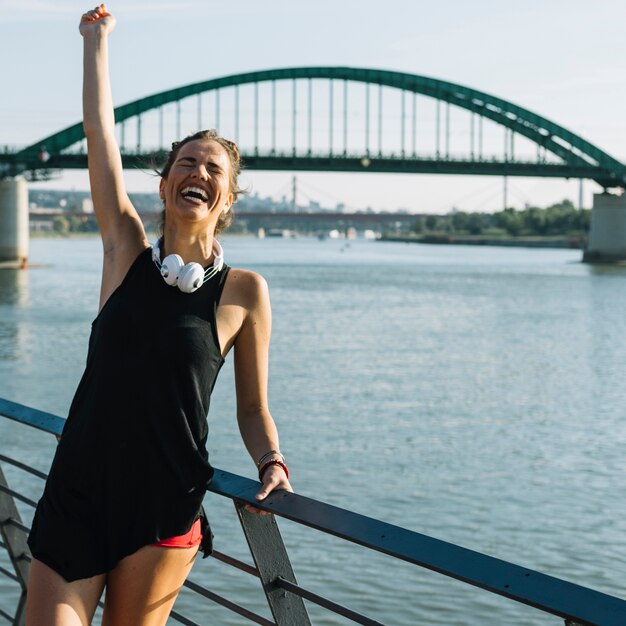 Excited woman raising her arms in front of river