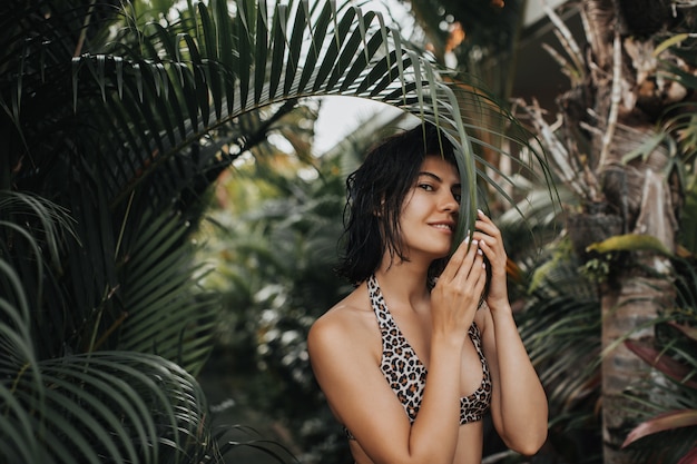 Excited woman with dark hair posing at exotic resort. Good-looking young woman having fun during vacation.