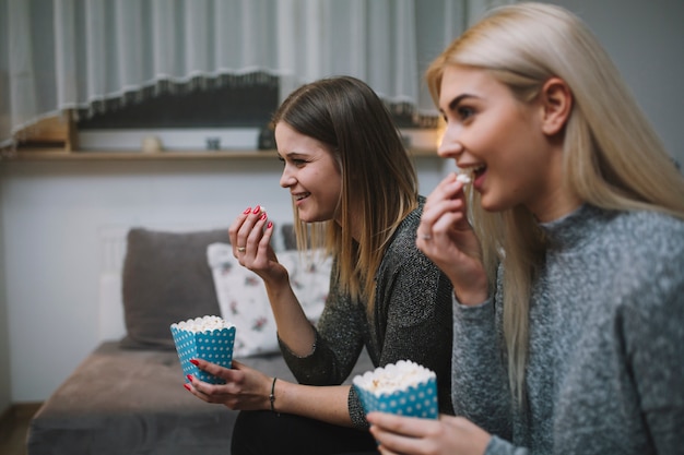 Excited women eating popcorn and watching film