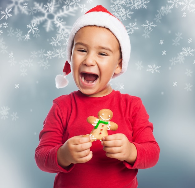 Excited young boy celebrating christmas with a gingerbread