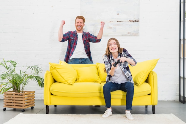 Free photo excited young couple enjoying playing video game at home