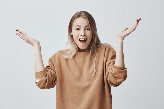 Free photo excited young female with blonde hair exclaiming. positive emotions, facial expressions