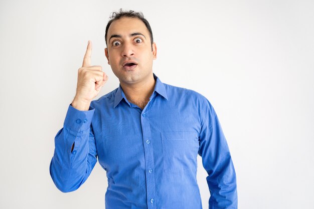 Excited young Indian guy raising finger and looking at camera