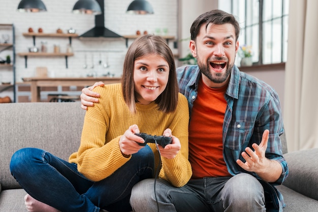 Excited young man sitting with her wife playing the video game