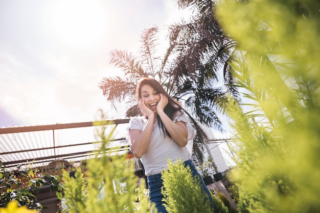 Excited young woman looking at plant in greenhouse