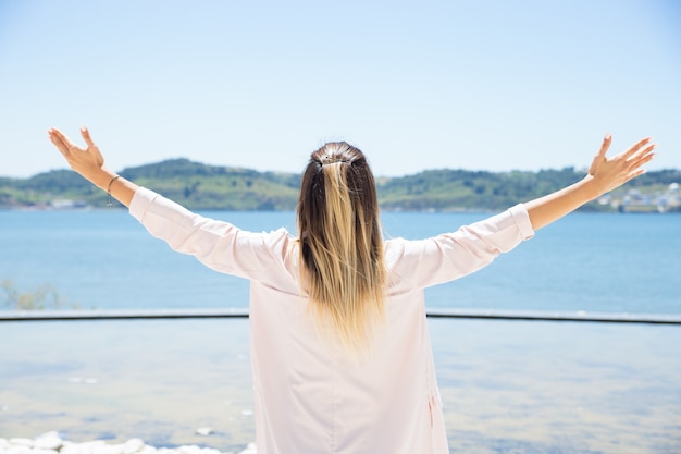 Excited young woman opening arms at landscape