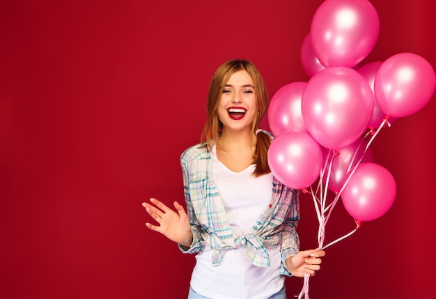 Excited young woman posing with pink air balloons