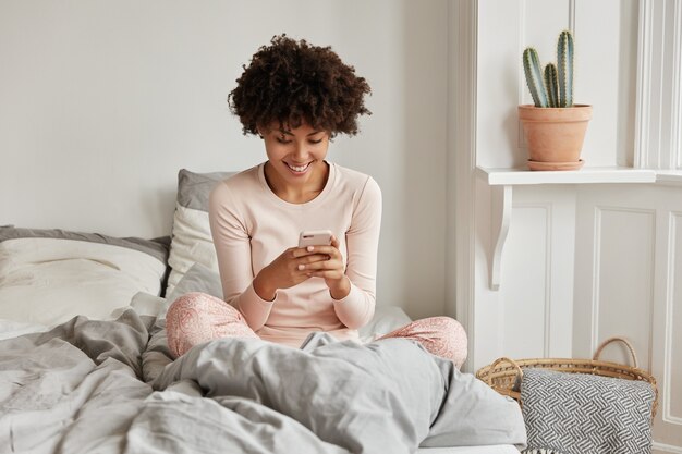 Excited young woman with her phone posing at home