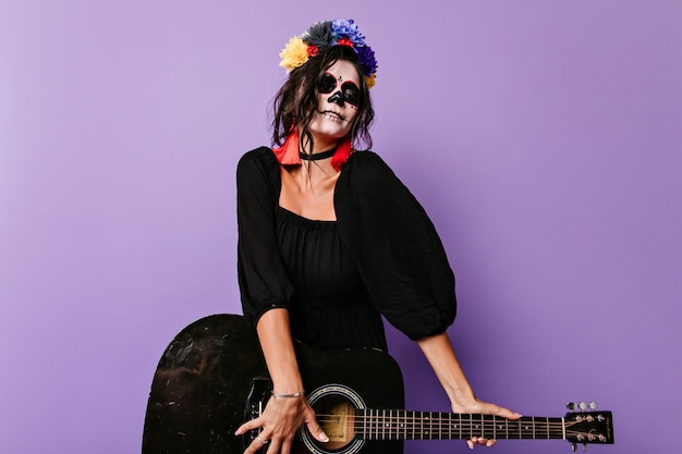 Free Photo excited zombie girl playing guitar. wonderful caucasian woman in halloween black costume having fun.